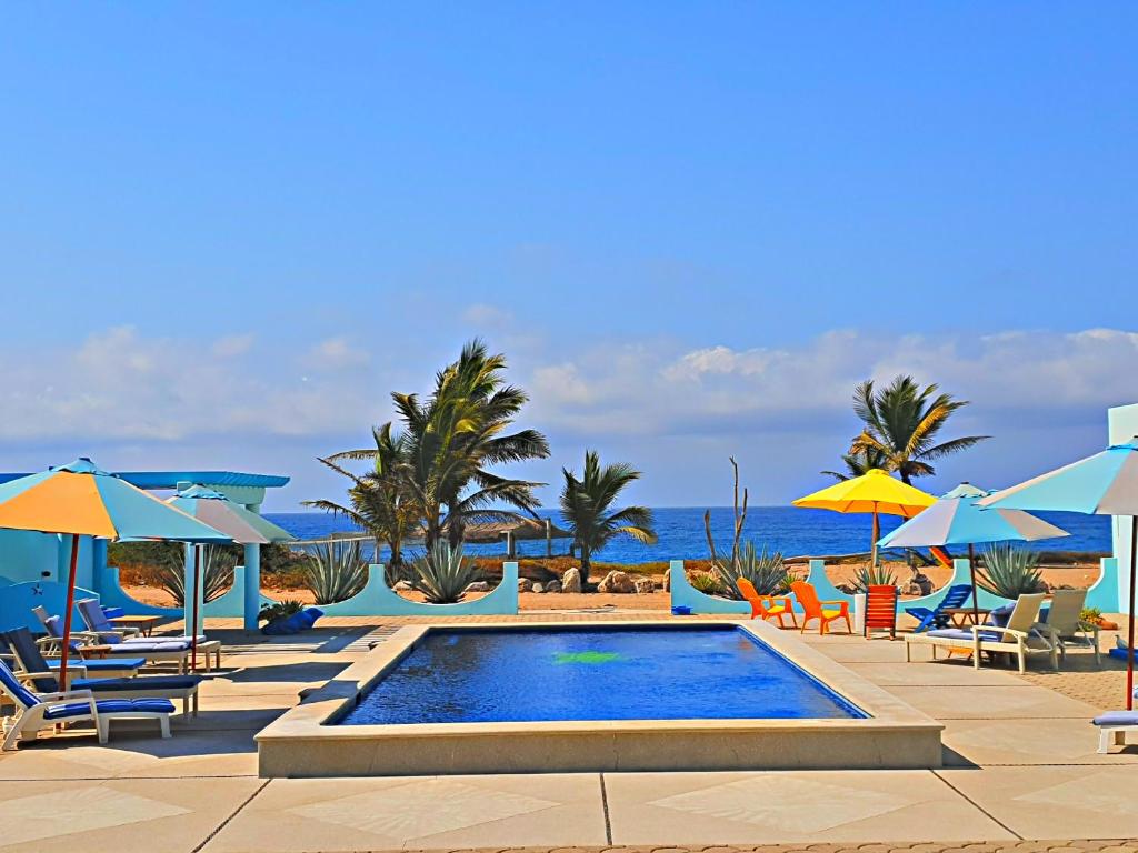 a swimming pool with chairs and umbrellas on the beach at Villa Star of the Sea in Barra de Navidad