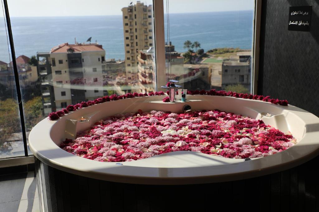 eine Badewanne mit Blumen vor dem Fenster in der Unterkunft Dolls Hotel By Eurostars - Adults only in Jounieh