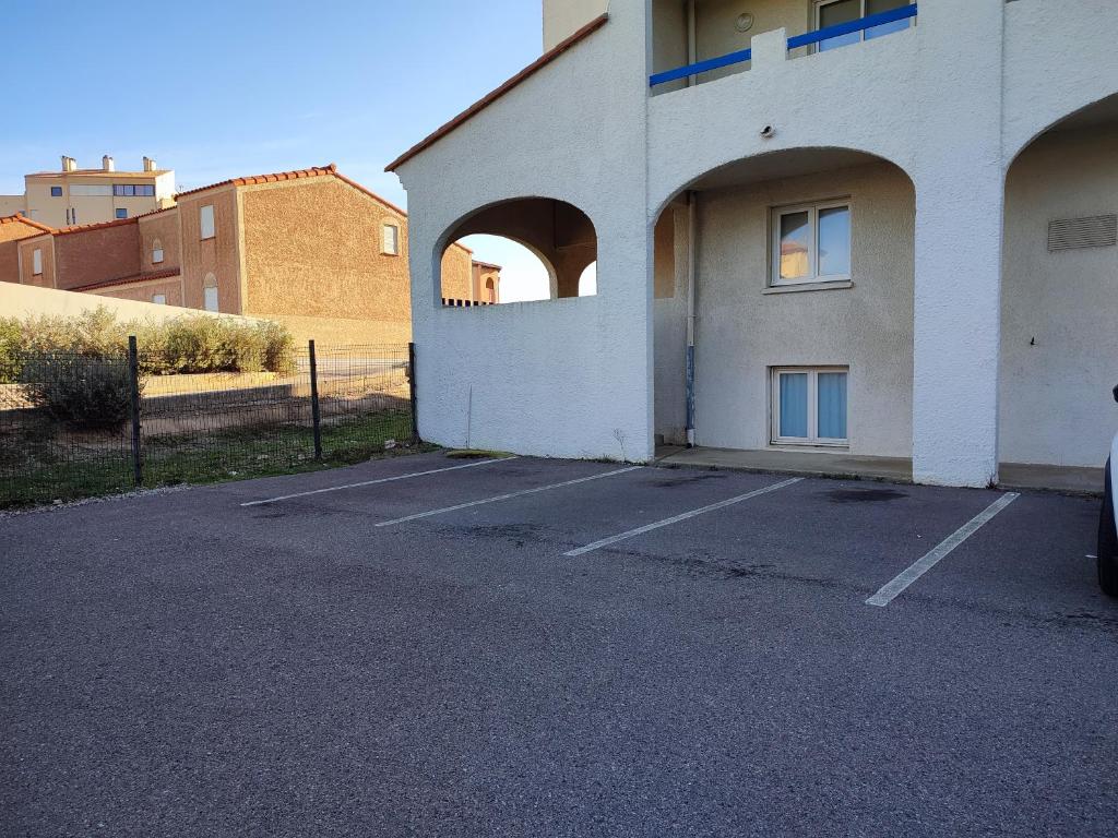 ein leerer Parkplatz neben einem weißen Gebäude in der Unterkunft Appartement T2 Ensoleillé au Barcarès in Le Barcarès