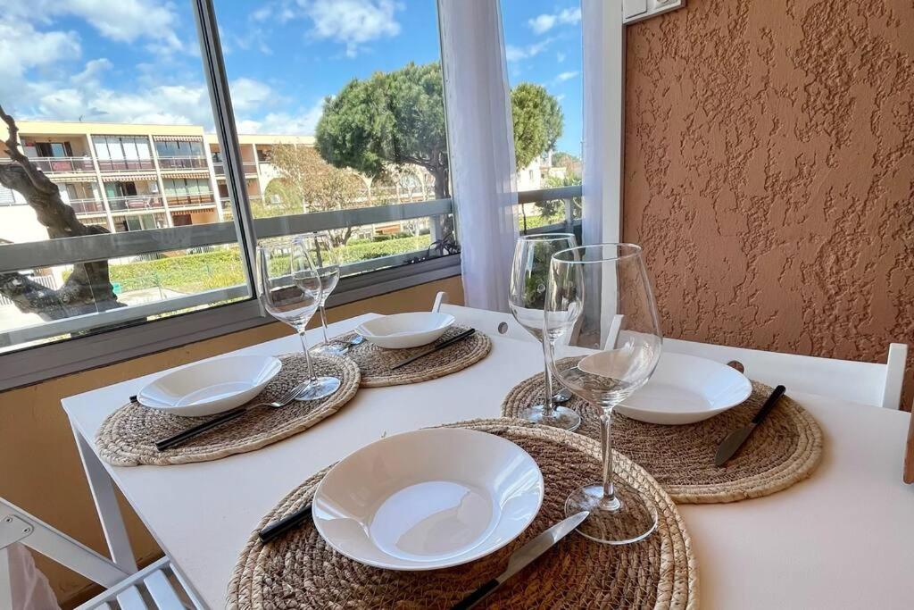 una mesa con platos y vasos en una mesa con ventana en Bord de Mer et Sérénité Bormes-les-Mimosas, en Bormes-les-Mimosas