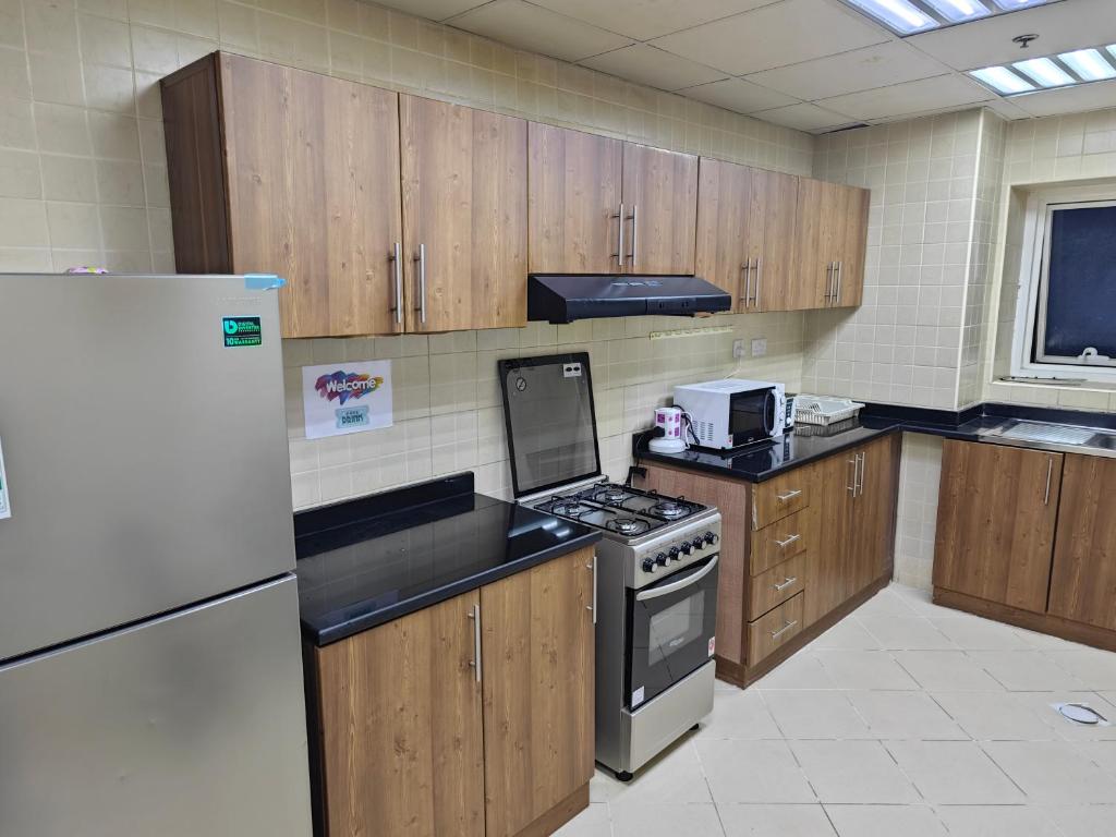 een grote keuken met houten kasten en een koelkast bij Pretty Room in Shared Apartment in Ajman 