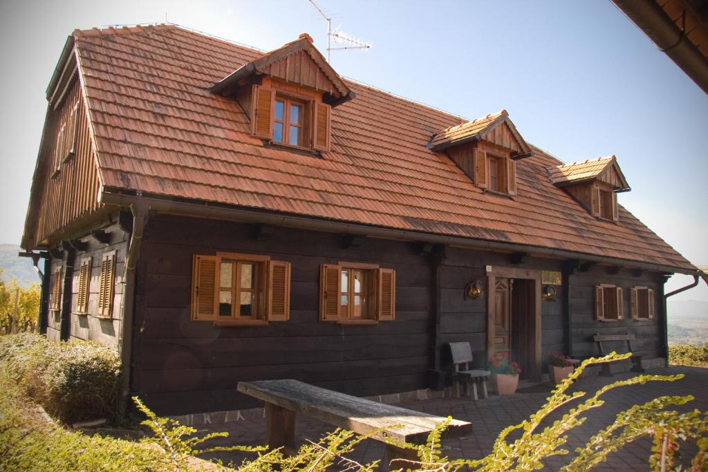 une maison en bois avec un banc devant elle dans l'établissement Apartmaji Žolnir, à Kostanjevica na Krki