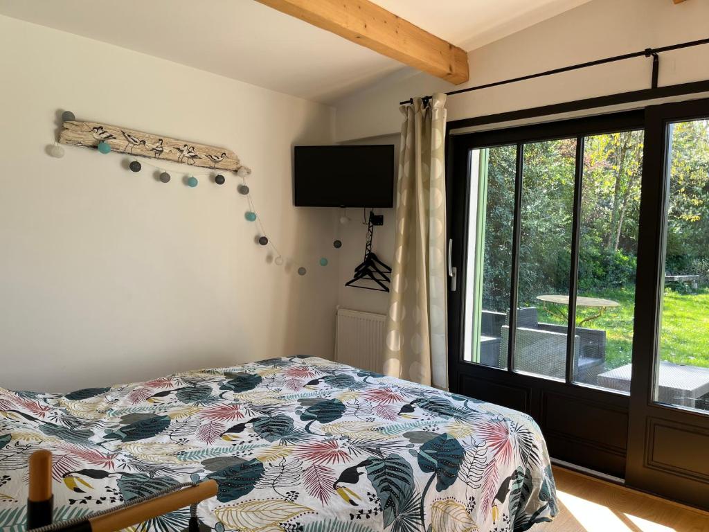 um quarto com uma cama e uma grande janela em Le P’tit Bois Doré em Blanquefort