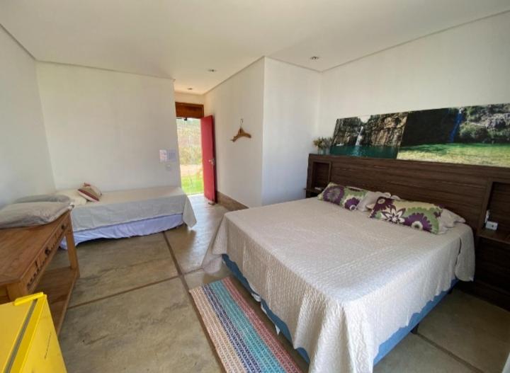 a bedroom with two beds and a painting on the wall at Pousada Espelho D'Água Capitólio in Capitólio