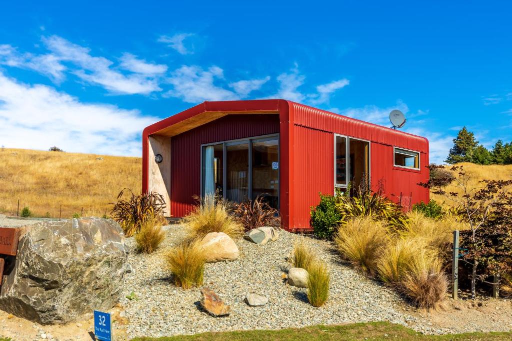 a red house on top of a hill with plants at The Red Nest - Lake Tekapo in Lake Tekapo