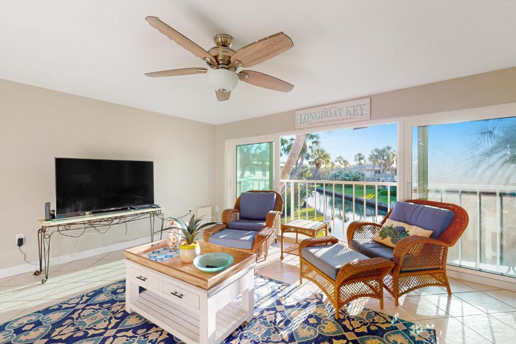a living room with a flat screen tv and chairs at Whitney Beach 149 in Longboat Key