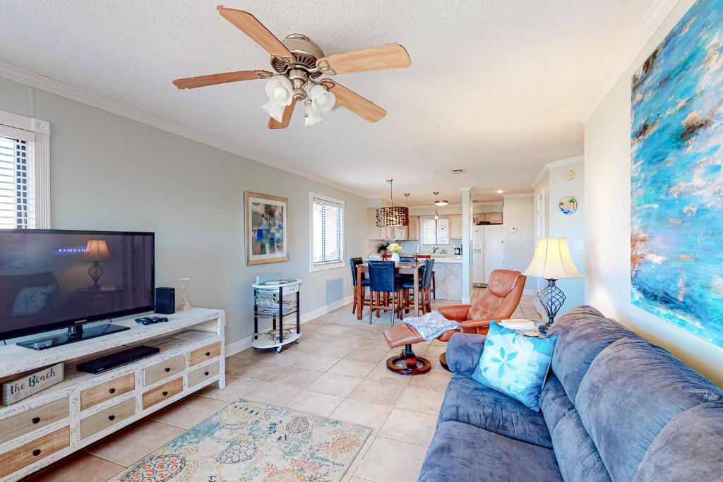 uma sala de estar com um sofá azul e uma televisão de ecrã plano em Sunset Harbor Palms 2-106 em Navarre