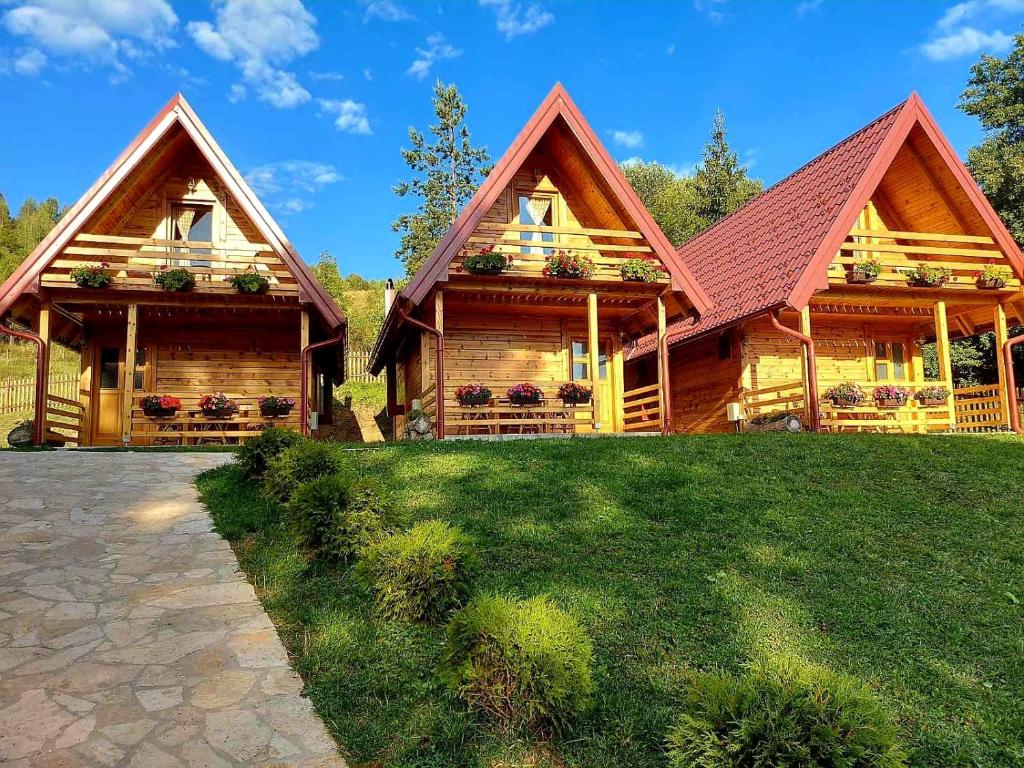 a log cabin with a green lawn in front of it at Drveni raj Uvac in Sjenica