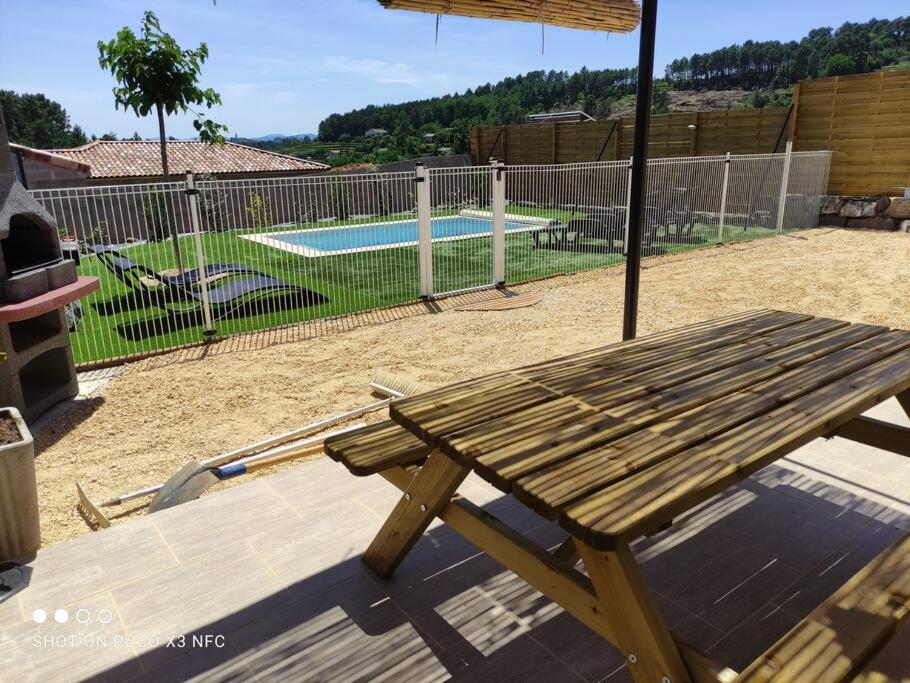 a wooden picnic table with an umbrella next to a pool at L&#39;Odyssée gîte avec sa piscine privative in Joyeuse
