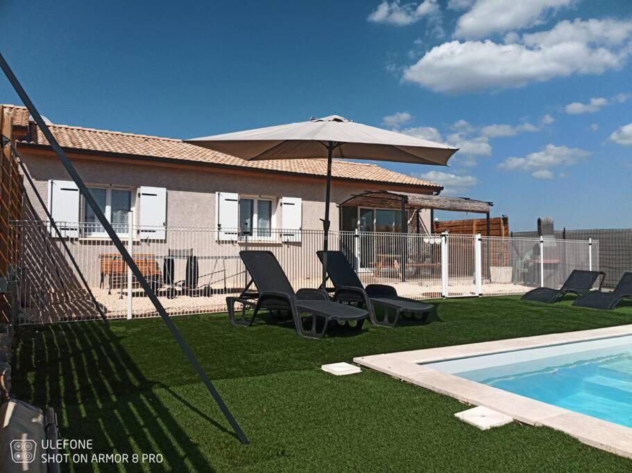 a patio with chairs and an umbrella next to a swimming pool at L&#39;Odyssée gîte avec sa piscine privative in Joyeuse