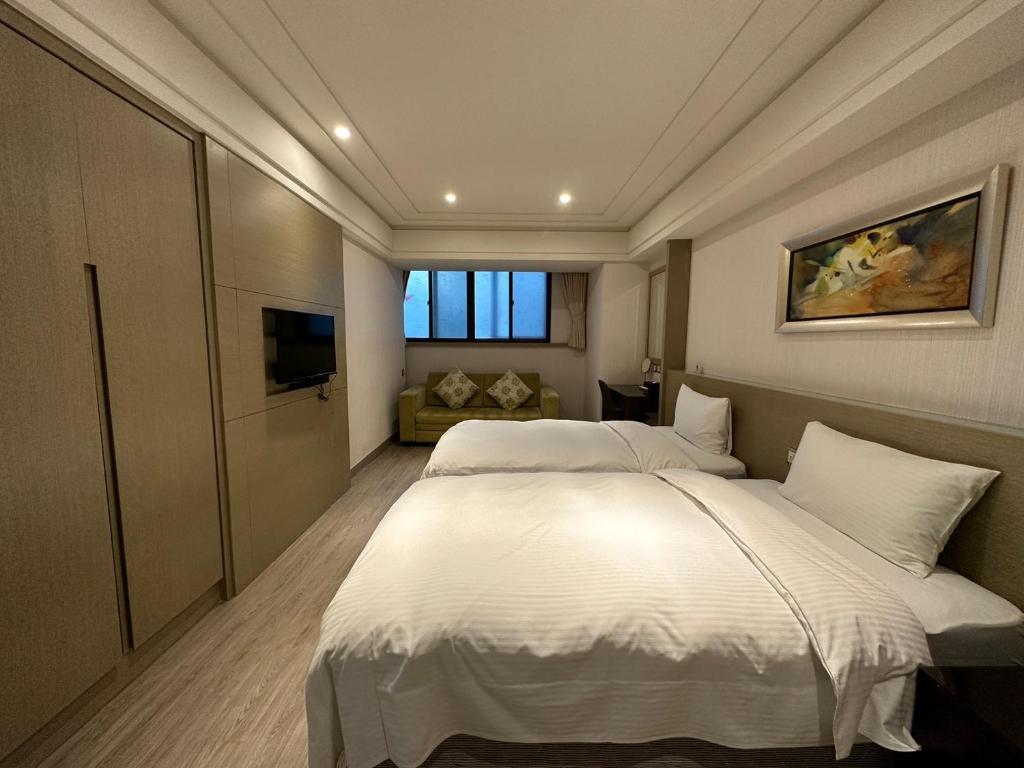 a bedroom with a large white bed and a television at Link World Hotel in Taipei