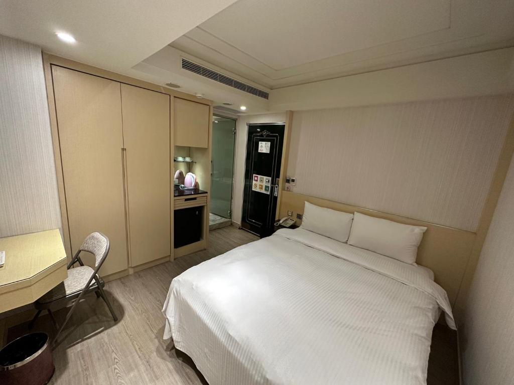 a bedroom with a bed and a desk and a kitchen at Link World Hotel in Taipei