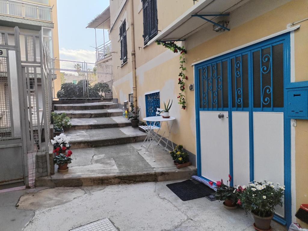 an alley with a blue door and a table and stairs at La tavernetta del Peo casa vacanze in Sanremo