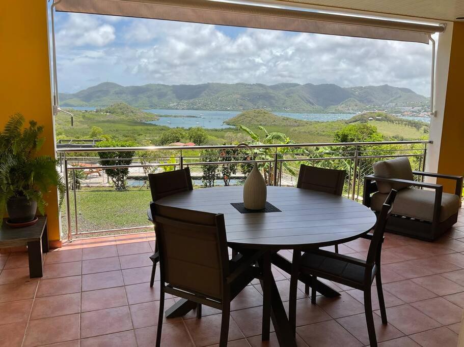 a table and chairs in a room with a large window at BAS DE VILLA PISCINE PETIT VERSAILLES SAINTE ANNE in Sainte-Anne
