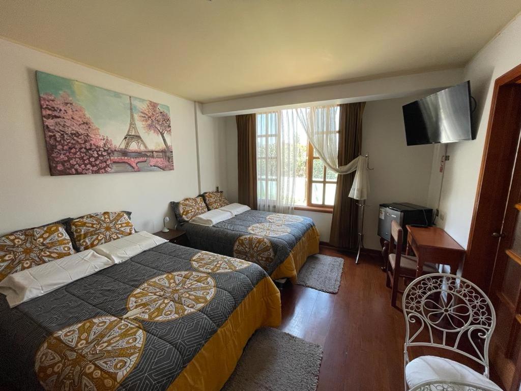 una camera d'albergo con 2 letti e una scrivania di The House a Tacna