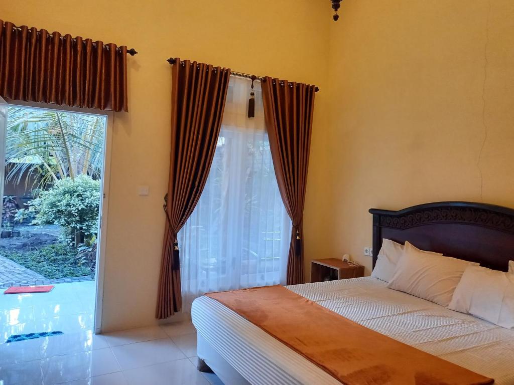 a bedroom with a bed and a large window at TelukBiru Homestay in Banyuwangi