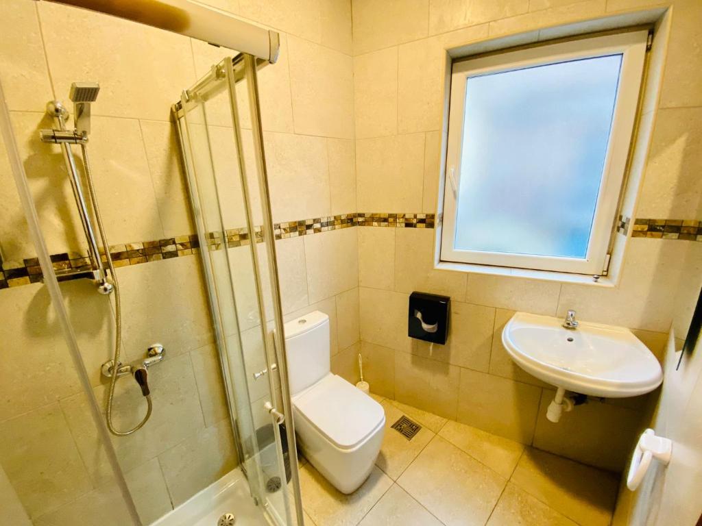 a bathroom with a toilet and a sink and a window at Marco Polo Party Hostel in St. Julianʼs
