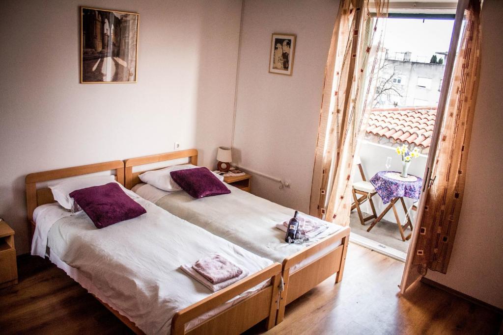 a bedroom with a bed with purple pillows and a balcony at Apartments Calendula Rubic in Split