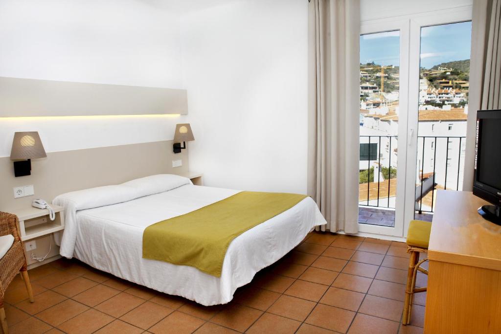 a hotel room with a bed and a balcony at Hotel Ubaldo in Cadaqués