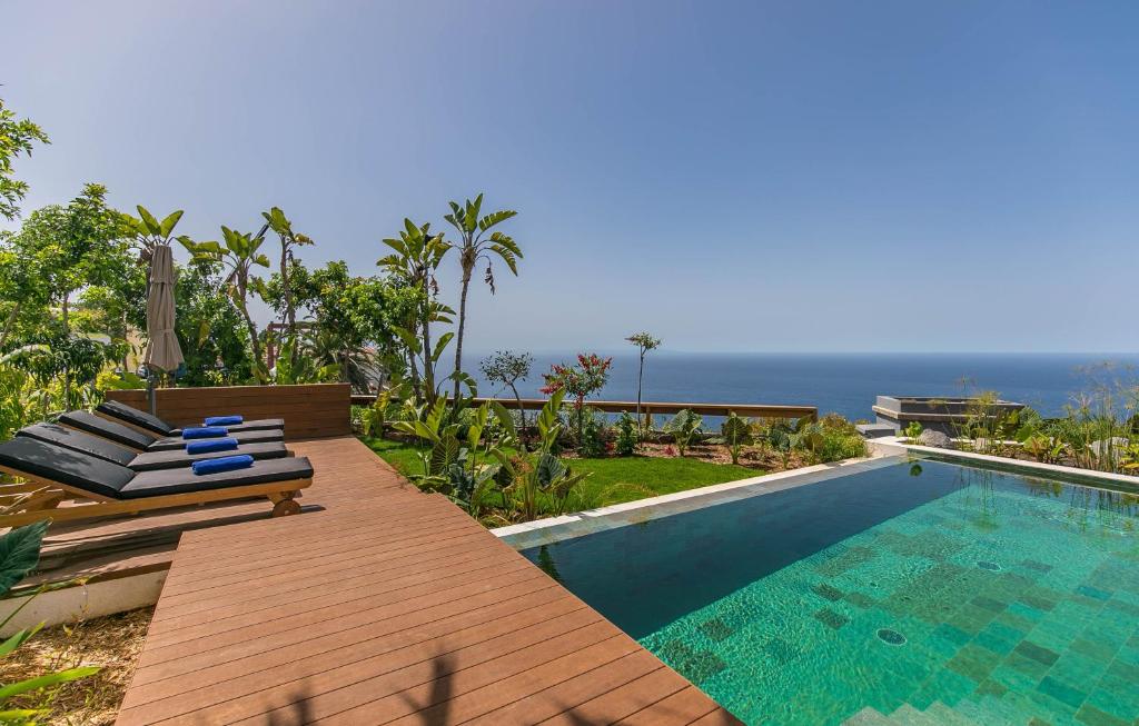 a swimming pool with lounge chairs next to the ocean at Serenity Villa on the Cliff with climatized pool in Sauzal