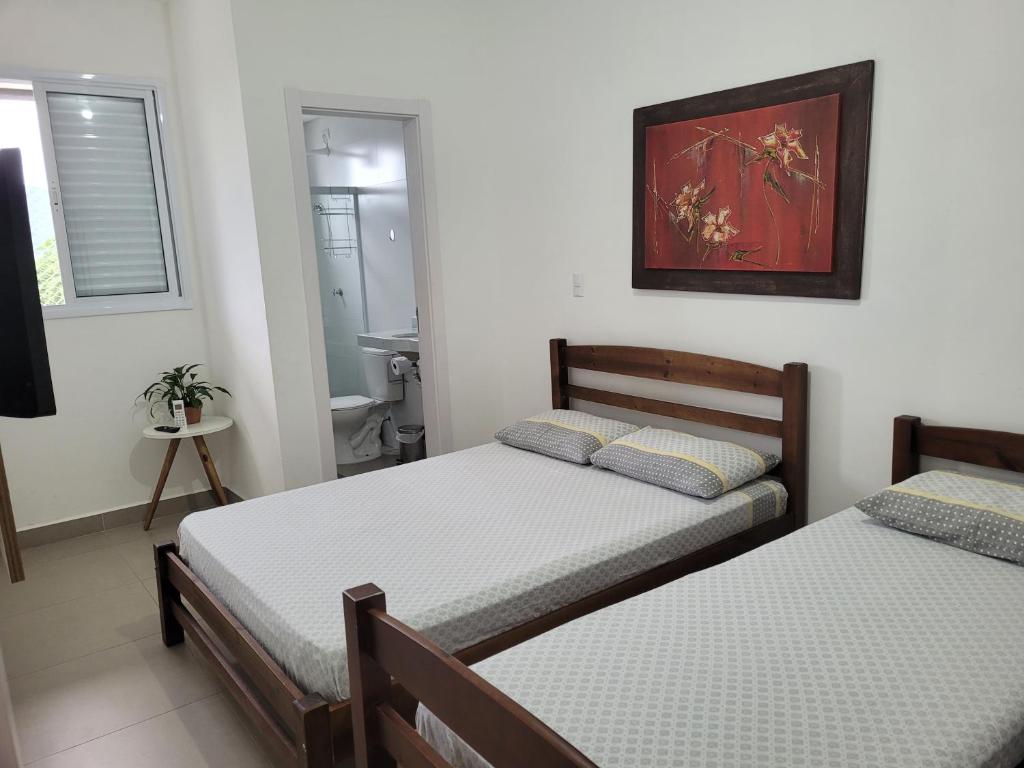 a bedroom with two beds and a bathroom at APARTAMENTO PRÓXIMO A PRAIA PISCINA E AREA GOURMET in Ubatuba