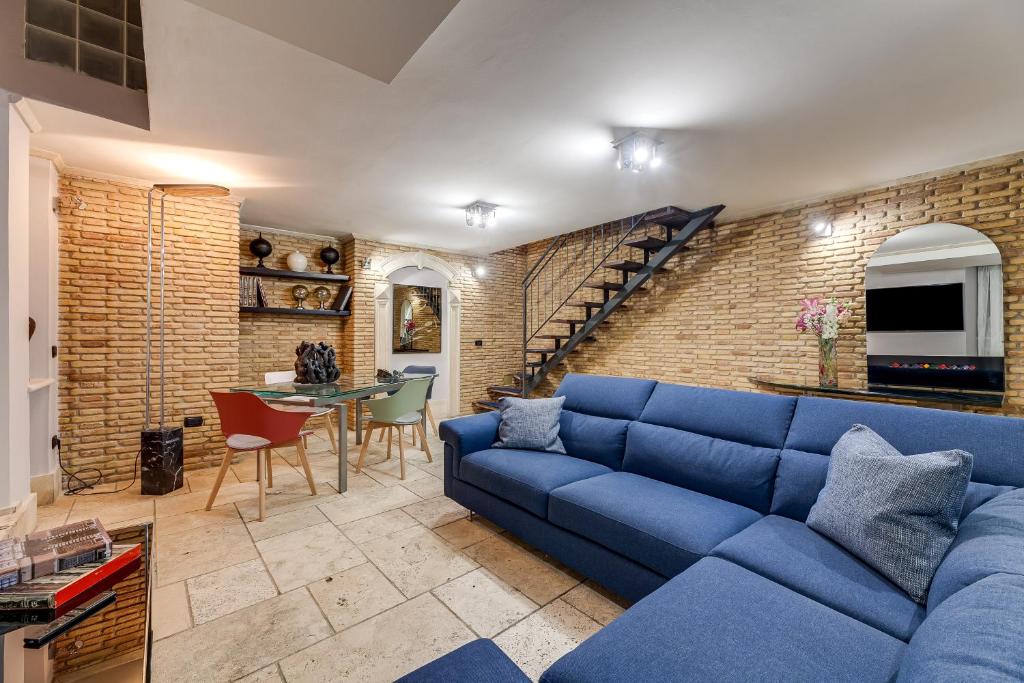Oliviero - Piazza Navona Apartment في روما: غرفة معيشة مع أريكة زرقاء وجدار من الطوب