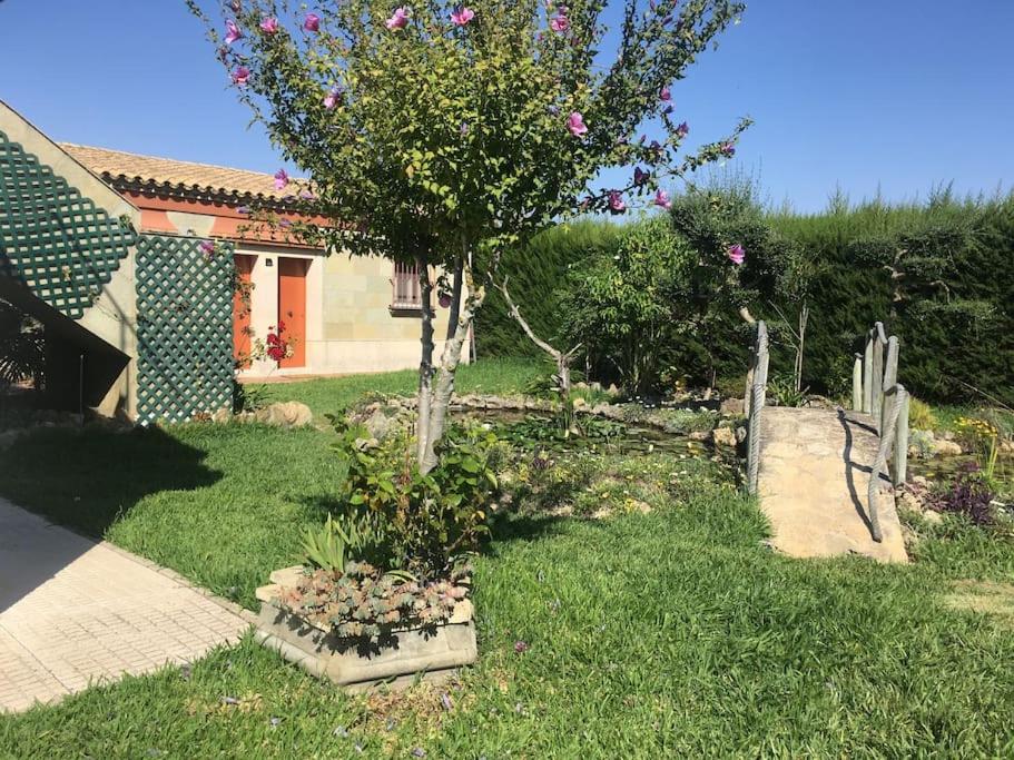 een tuin met een boom en bloemen voor een huis bij Tranquil apartment in Chiclana La Barrosa in Chiclana de la Frontera
