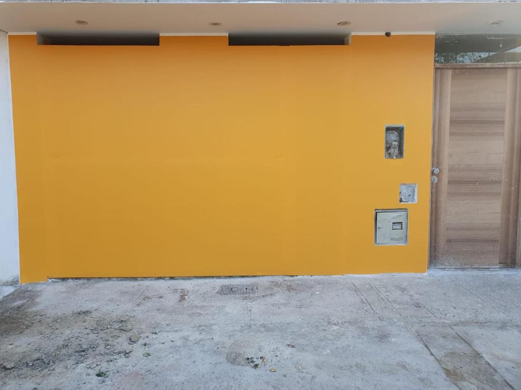 eine gelbe Wand mit zwei Garagentüren an einem Gebäude in der Unterkunft Casa La Ruta Jardines in Pisco
