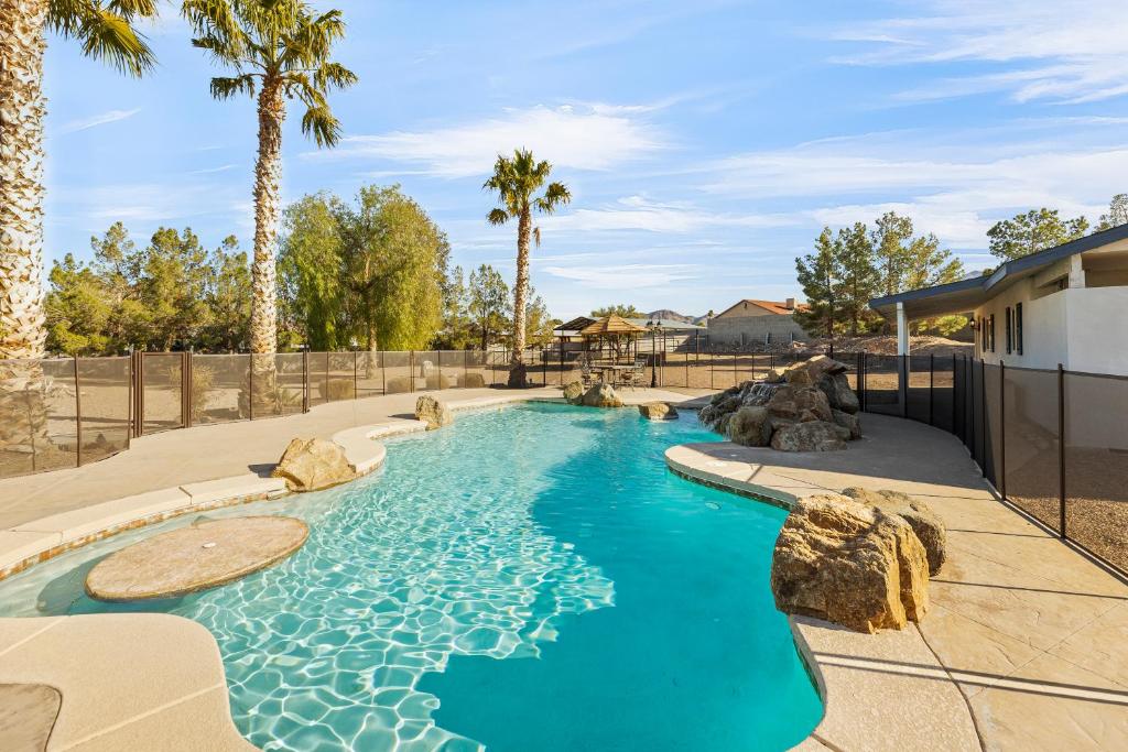 een zwembad in een tuin met palmbomen bij Spacious Desert Getaway! 1-Story, 5BR, 3 Master Suites, Casita, Pool, EV, Game Room in Las Vegas