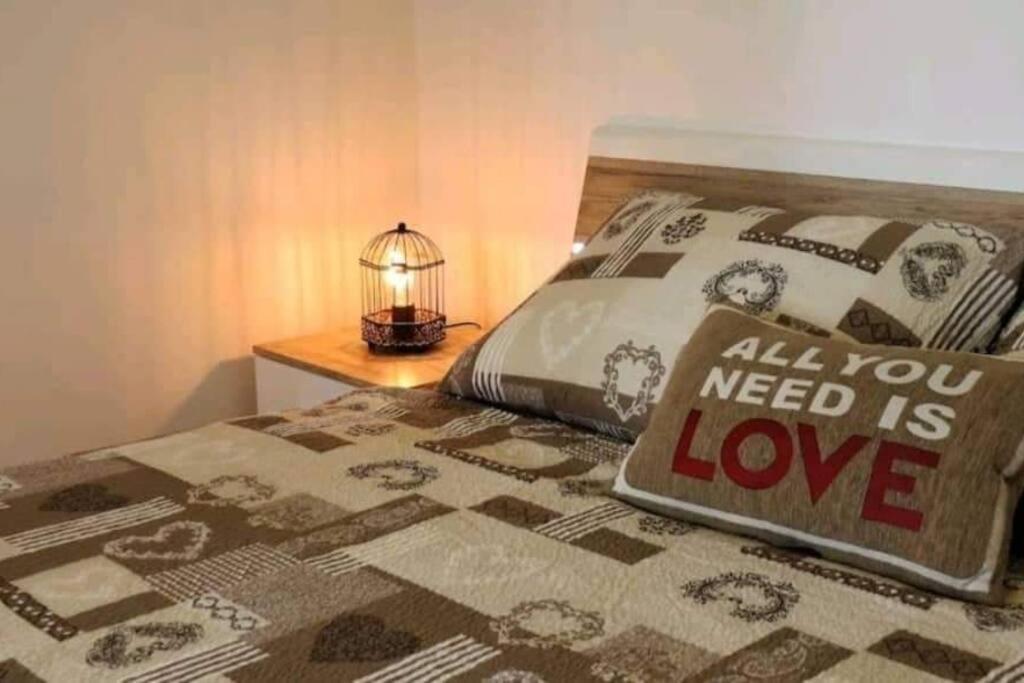 Una cama con una almohada que dice que todo lo que necesitas es amor en Apartment near Colloseum, en Pula