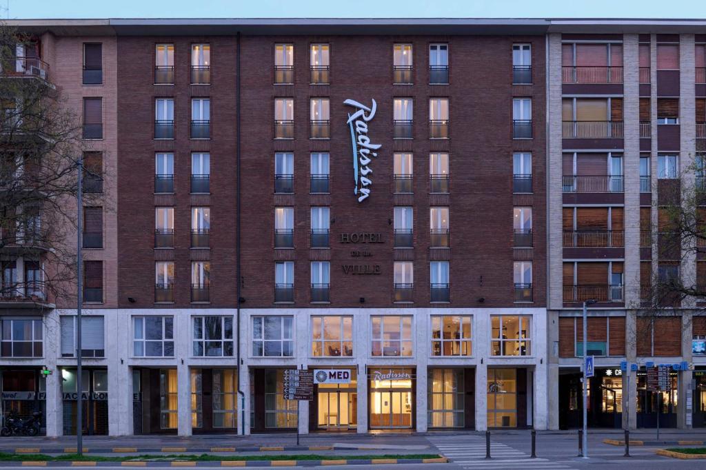 un grande edificio in mattoni con un cartello sopra di Radisson Hotel Ferrara a Ferrara