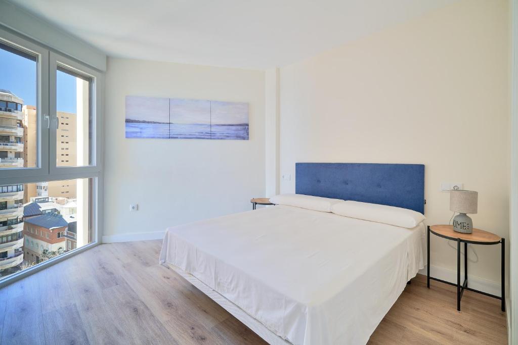 biała sypialnia z dużym łóżkiem i oknem w obiekcie Impresionante apartamento en Playa de la Malagueta w Maladze