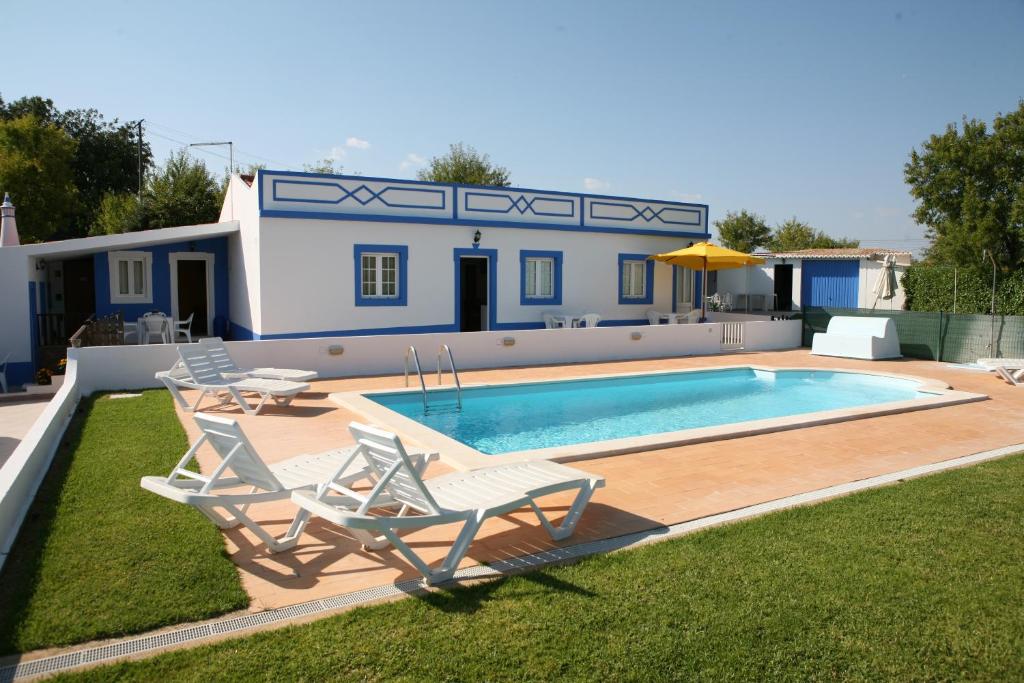 a swimming pool with two chairs and a house at Quinta das Amendoeiras in Albufeira