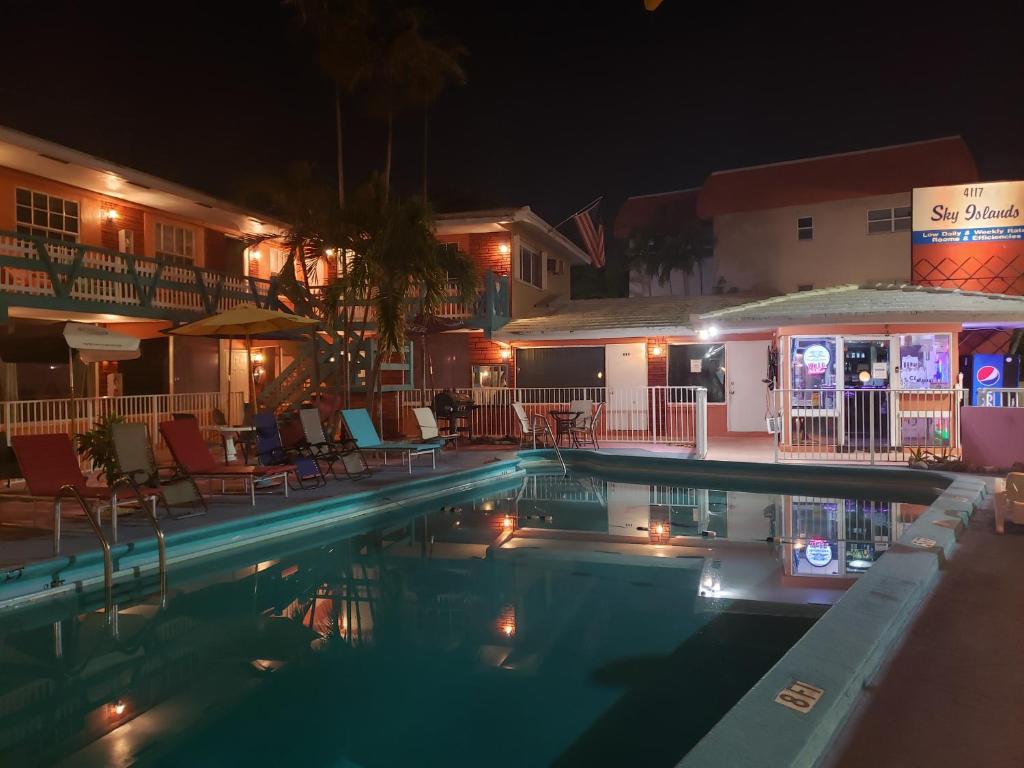 una piscina por la noche con sillas y sombrillas en Sky Islands Beach, en Fort Lauderdale