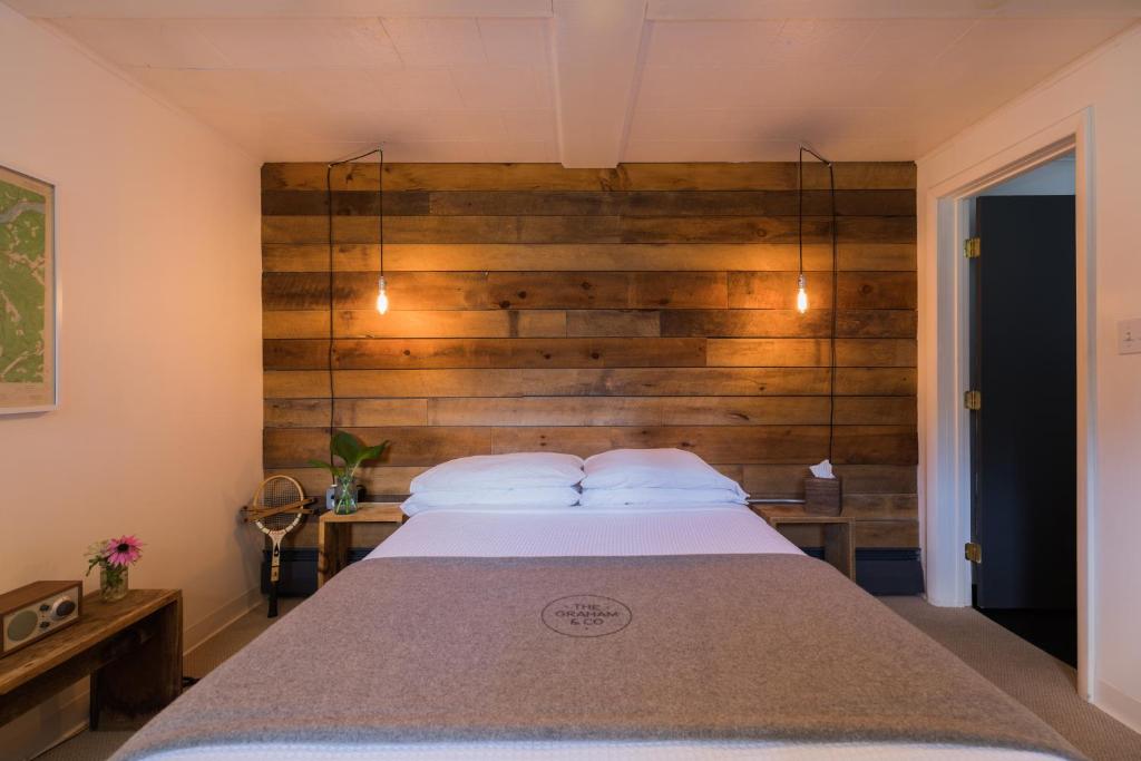 ein Schlafzimmer mit einem Bett mit einer Holzwand in der Unterkunft The Graham & Co. in Phoenicia
