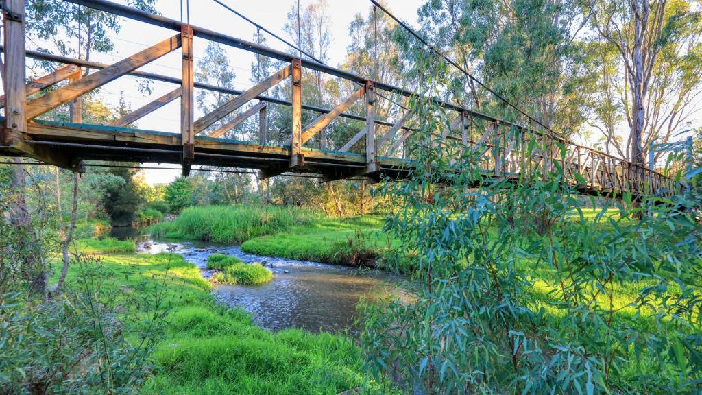 a bridge over a river with a creek at Alpine Riverside Accommodation in Myrtleford