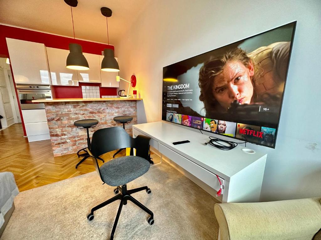 a living room with a desk with a large screen at Super BEAUTY metro WiFi 65’TV Netflix HBO AppleTV+ in Warsaw