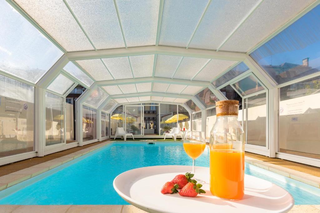 a glass of orange juice and strawberries on a plate next to a swimming pool at 731 Costa Cabral Metro Residence in Porto