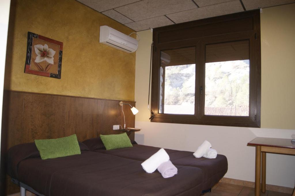 Un dormitorio con una cama con almohadas verdes y una ventana. en HOTEL FAMILIAR BAGA, en Bagá