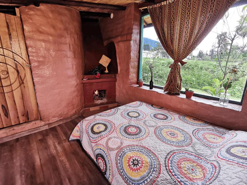 a bedroom with a bed and a window at Uchilla Wasi - Casa Suaya La Esperanza in Ibarra