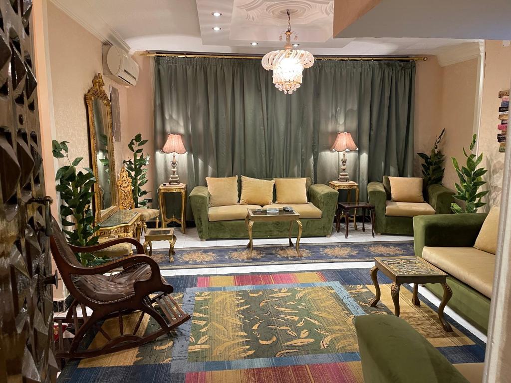 una sala de estar con muebles verdes y una lámpara de araña. en Fancy apartment close to airport fully furnished, en El Cairo