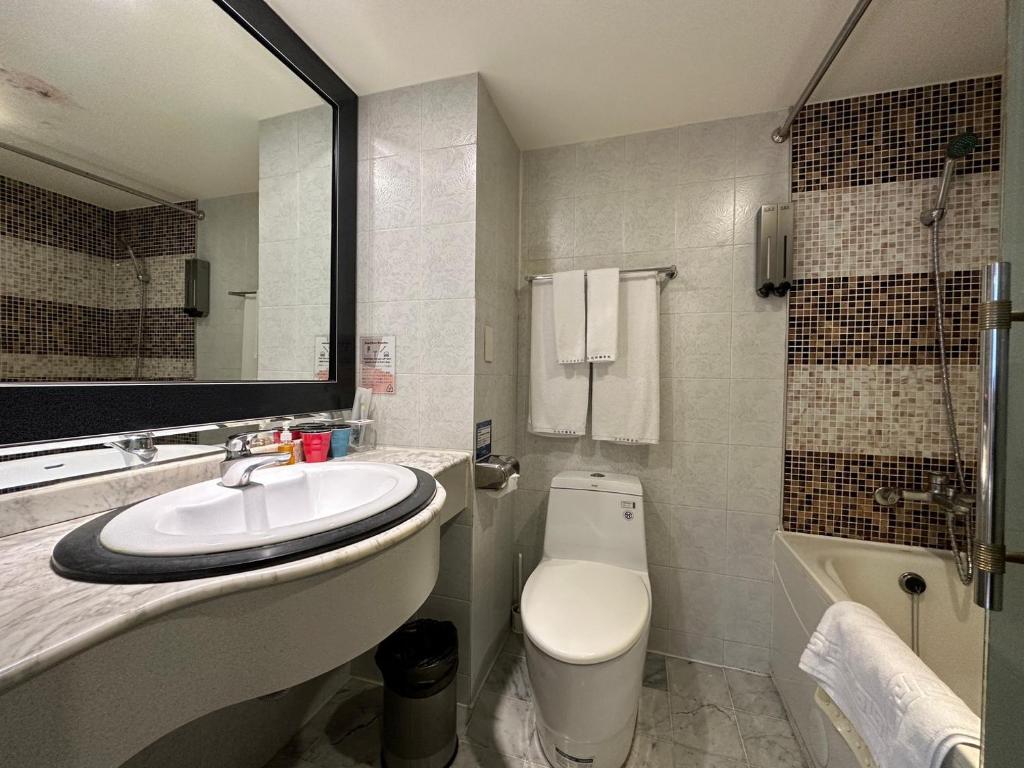 a bathroom with a sink and a toilet and a tub at Link World Hotel in Taipei