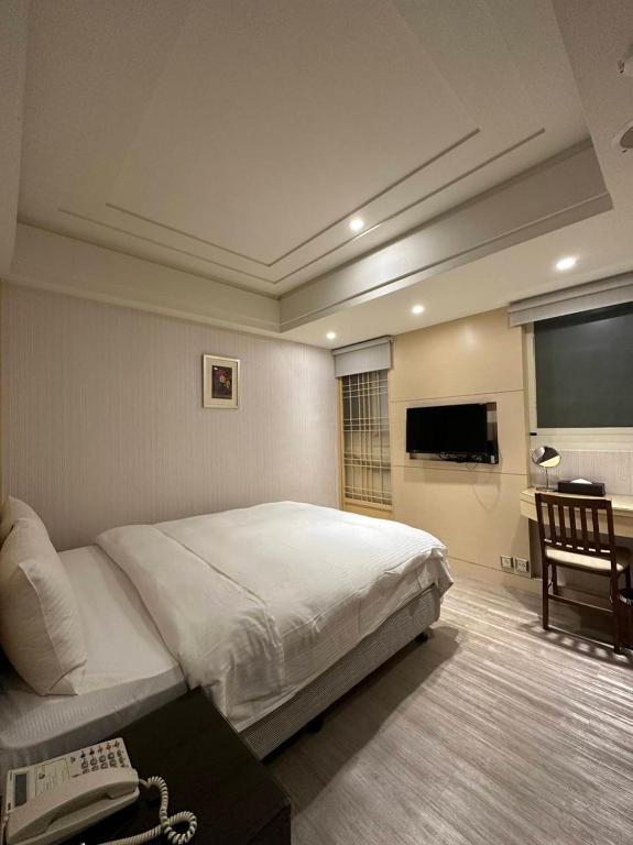 a bedroom with a bed and a telephone and a desk at Link World Hotel in Taipei