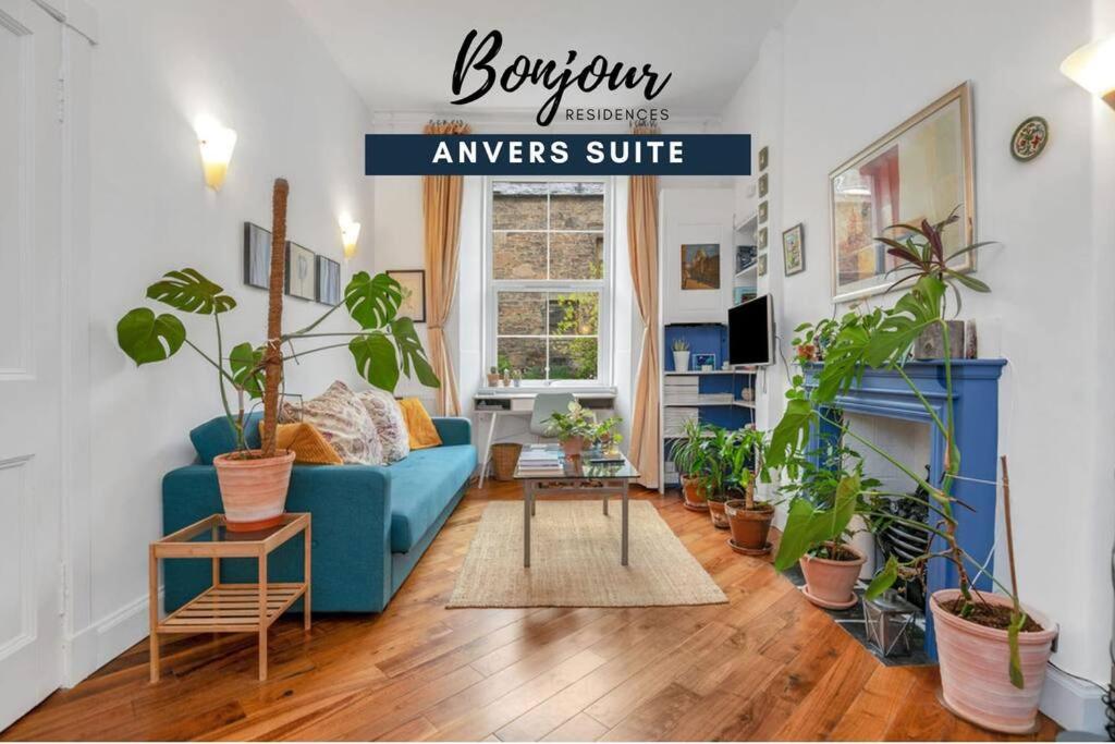 a living room with a blue couch and lots of plants at Anvers Suite in Edinburgh