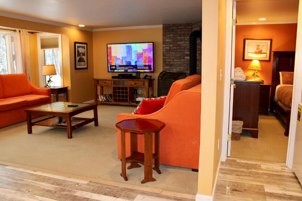 sala de estar con muebles de color naranja y TV de pantalla plana. en Condo 7 Slopeside With Private Sauna and Hot Tub en Killington