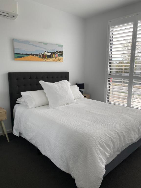 a white bed with white sheets and a window at Beachside Apartment 108 in McCrae