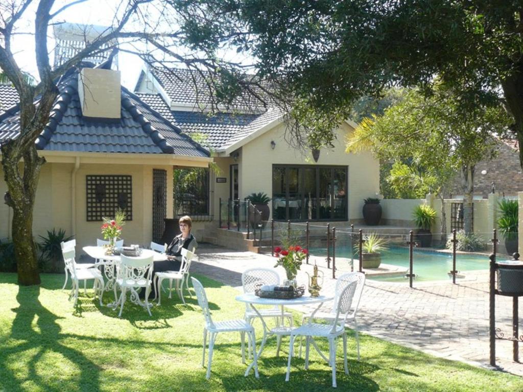 a woman sitting at a table in front of a house at Villa Xanelle Boutique Guest House in Centurion