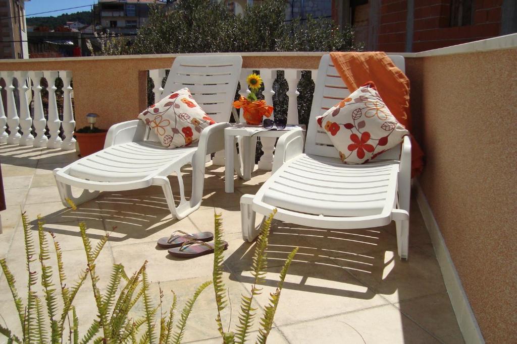 3 sillas blancas con almohadas en el patio en Apartments Bulicic, en Trogir