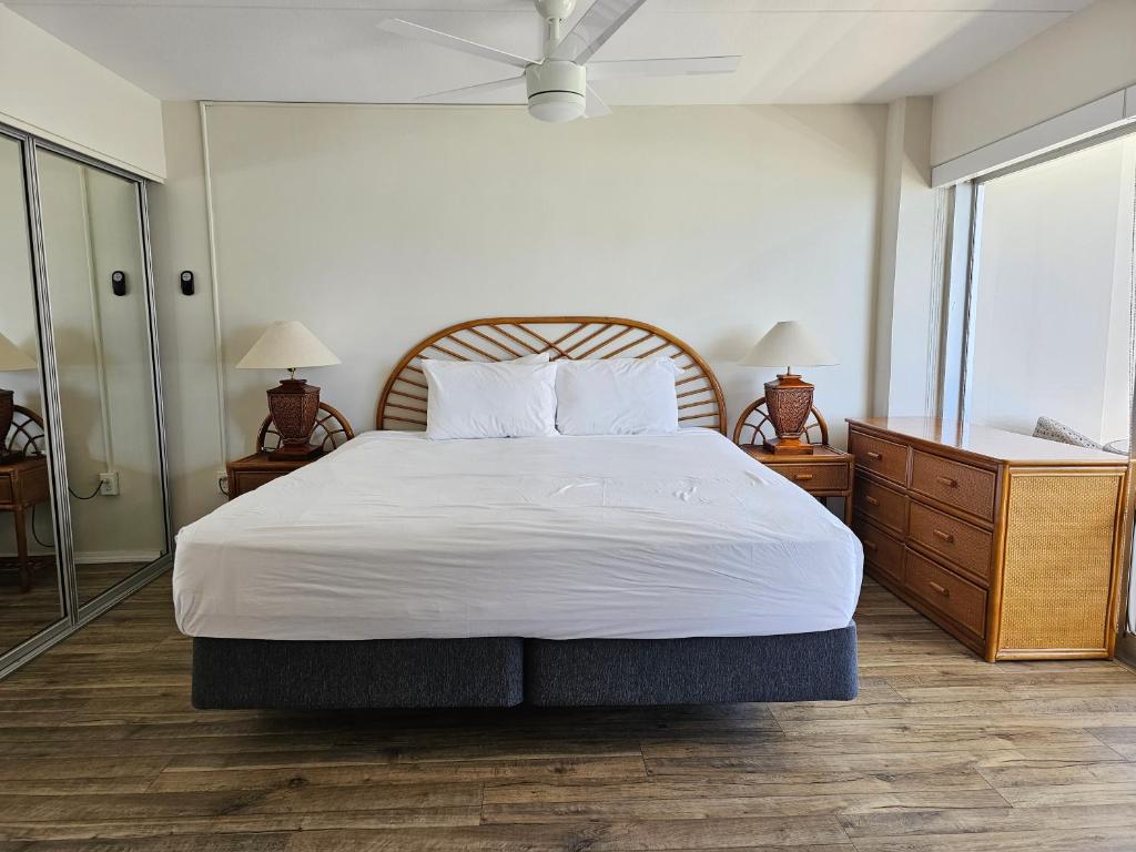 Cette chambre comprend un grand lit avec des draps blancs et un ventilateur. dans l'établissement Ilikai Tower 1340 Lagoon View 1BR, à Honolulu