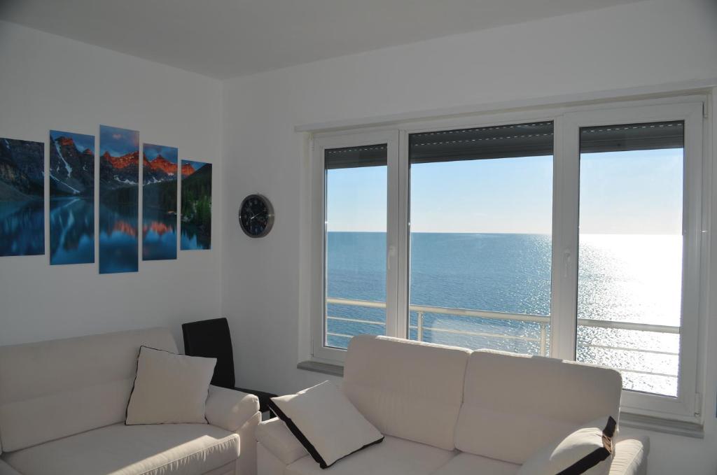 uma sala de estar com um sofá branco e duas janelas em Home Sweet Home by the Sea - 060 em Durrës